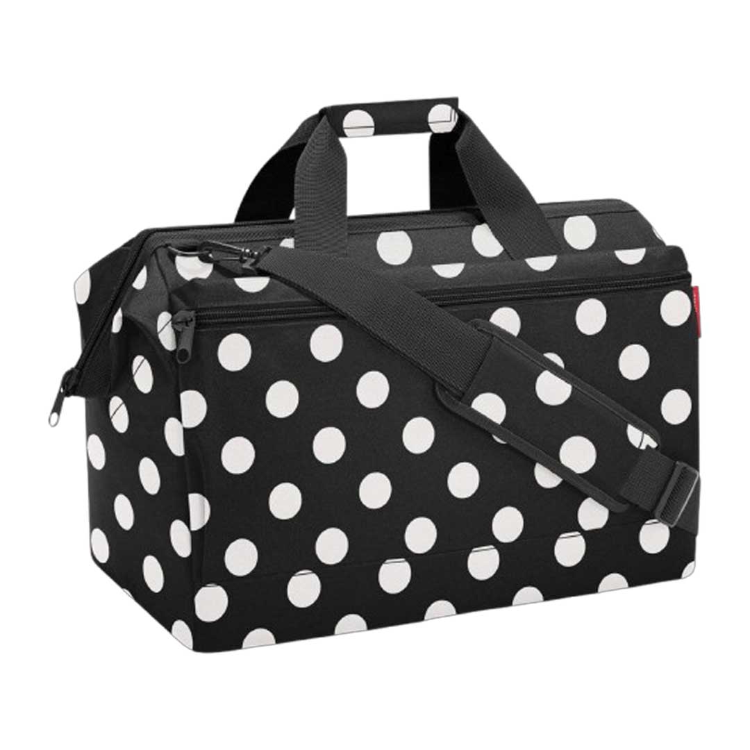 Black rectangular duffel bag with large white polka dots, two top handles and a detachable shoulder strap