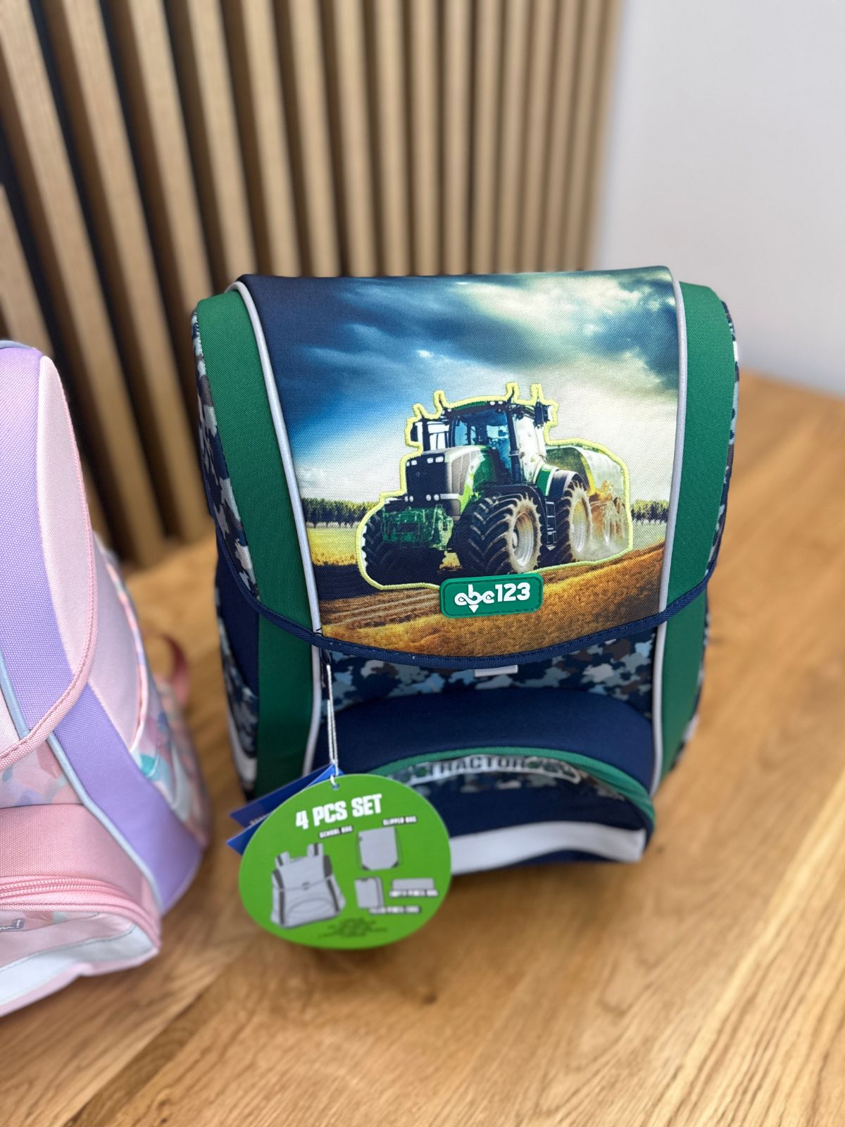 Backpack with a green front flap showing a large tractor illustration and a '4 PCS SET' tag (kids' school bag).