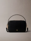 Black leather handbag with gold hardware and a top zipper, visible CK logo on the front.