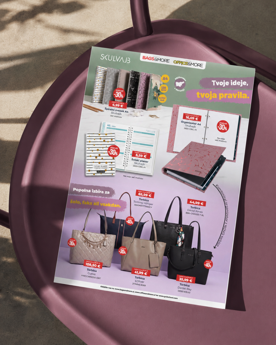 Open promotional catalog showing notebooks, planners and handbags on a pink chair outdoors, with the slogan 'Tvoje ideje, tvoja pravila' visible on the page.